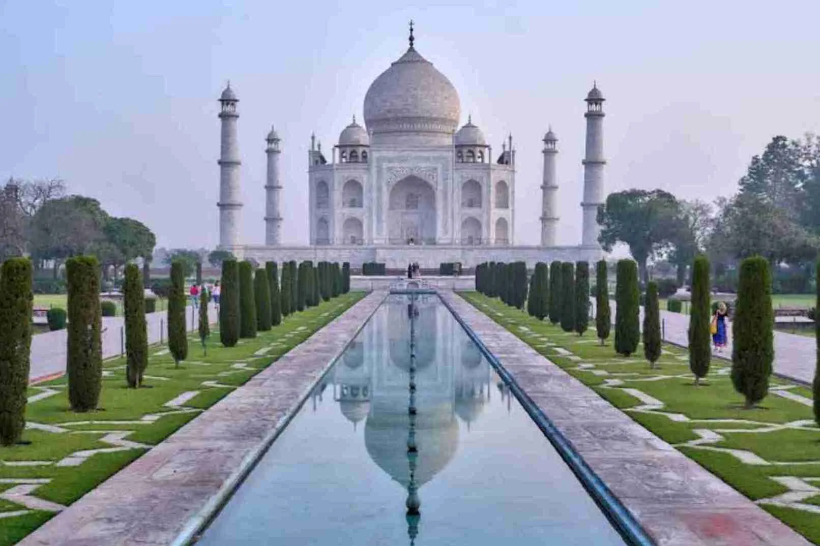 A water lake green trees and white color taj mahal which has big dome on top historical place