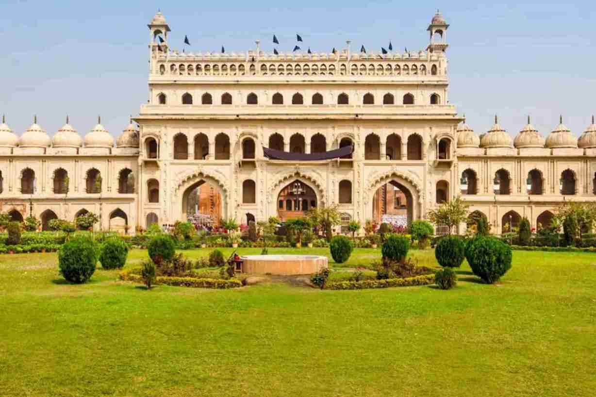 A big palace standin on the green grass land and plants in front of palace