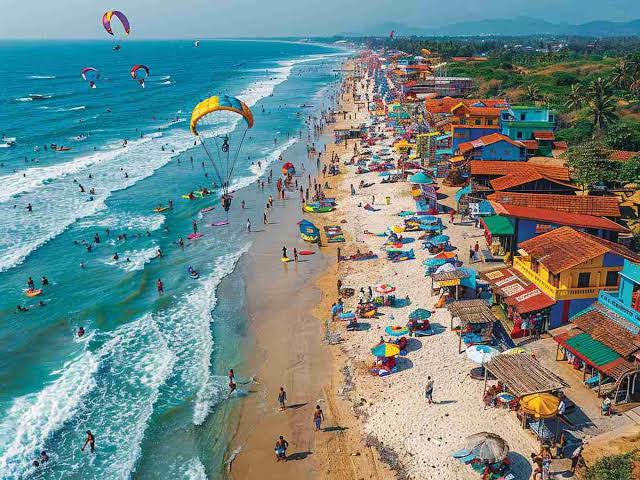 Goa beach where some huts are there and people bathing in sea watm Winter Tourism in India