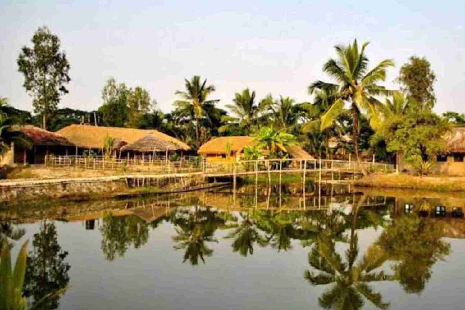 Two huts near the lake and palm trees un सुंदरबन राष्ट्रीय उद्यान