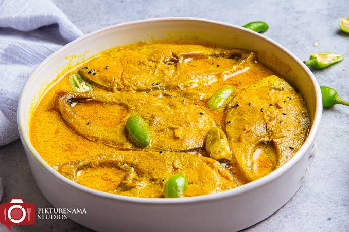 shorshe ilis a bengali dish looks yelloish color with green chilli वेस्ट बंगाल के लोकप्रिय व्यंजन