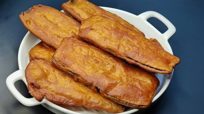 Beguni is bengali dish and serve on white plate and has 6 pieces of beguni in brown color in वेस्ट बंगाल के लोकप्रिय व्यंजन