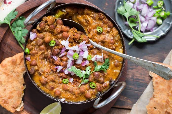 Chana Ghugni served on plate and one spoon with chopped onion in बिहार के लोकप्रिय व्यंजन