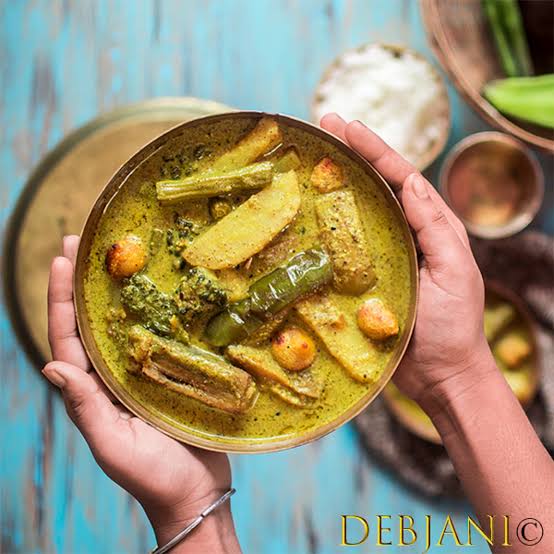 Shokto is a bengali dish a hand is taken bowl with gravy in the bowl yelloish in color in वेस्ट बंगाल के लोकप्रिय व्यंजन